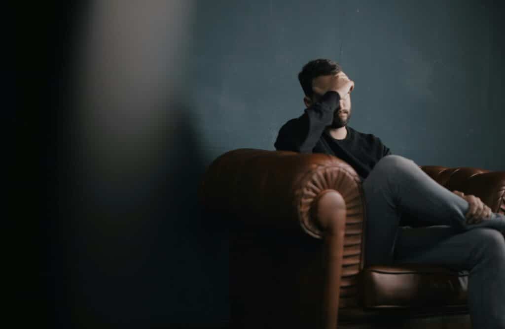 Man sitting on couch having a migraine