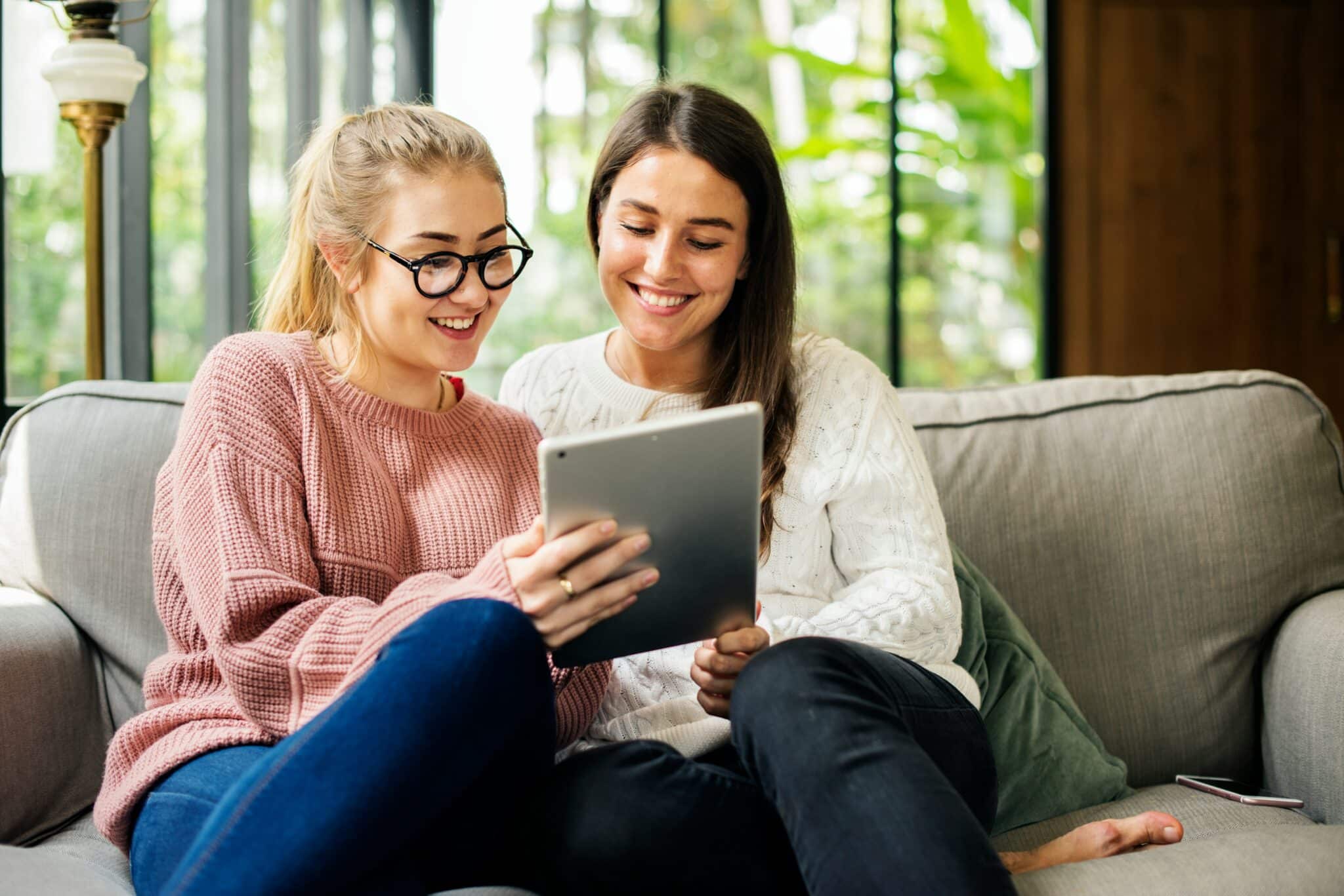 Two women sitting on a couch smiling