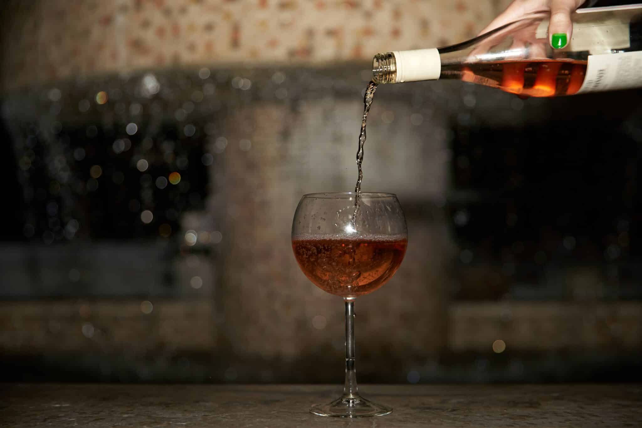 Someone pouring wine into a wine glass